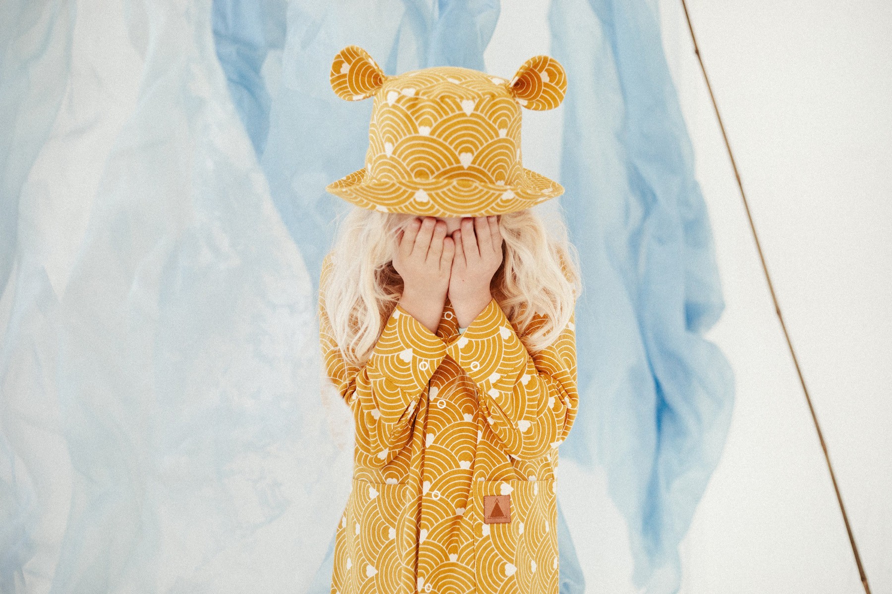 Children's hat with ears - waves on a mustard-yellow background